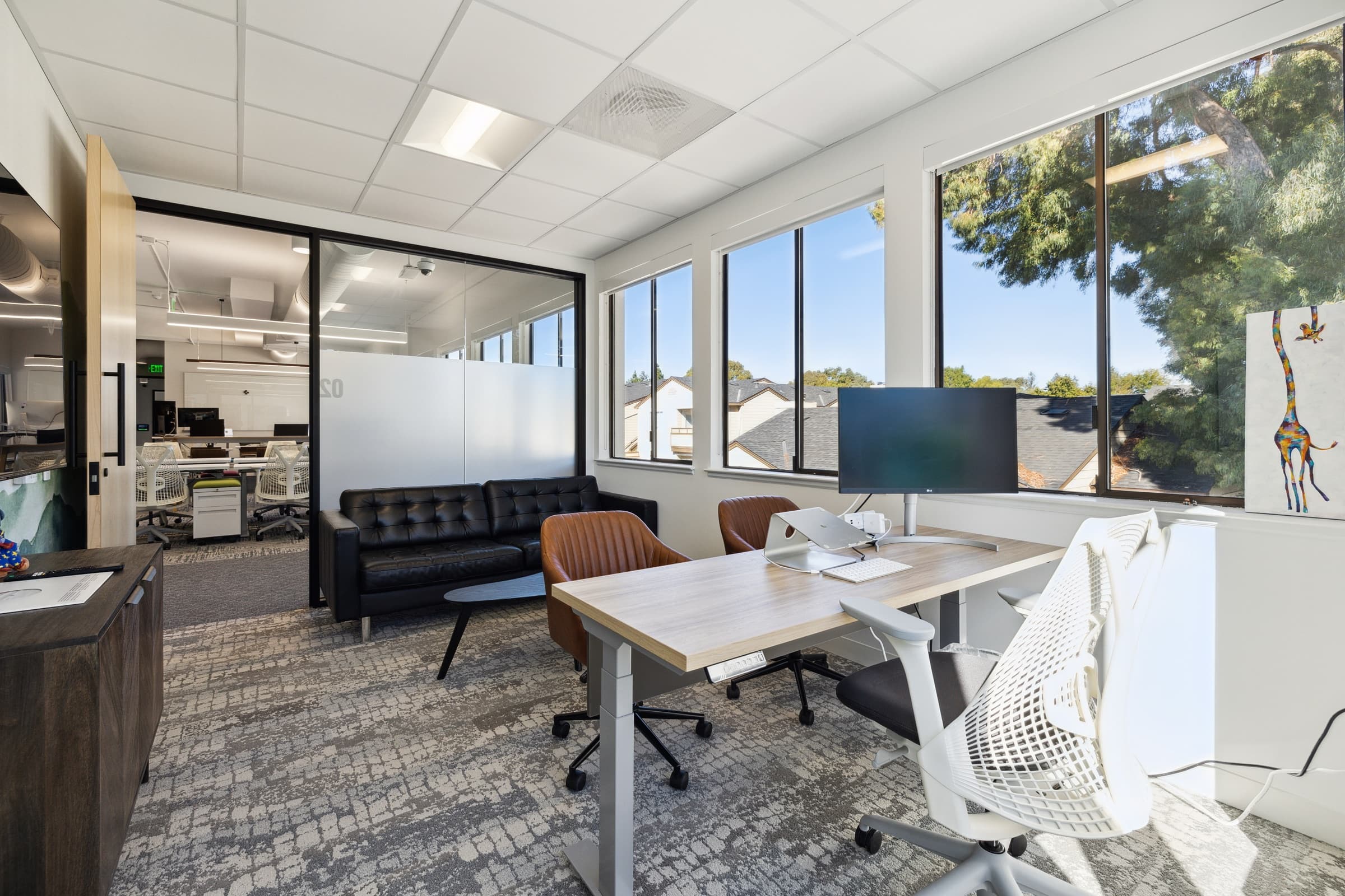 Corner private office with lounge seating and two walls of windows